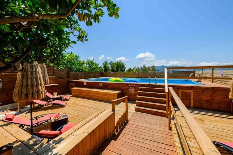 Piscina con solarium in legno e vista sulle colline